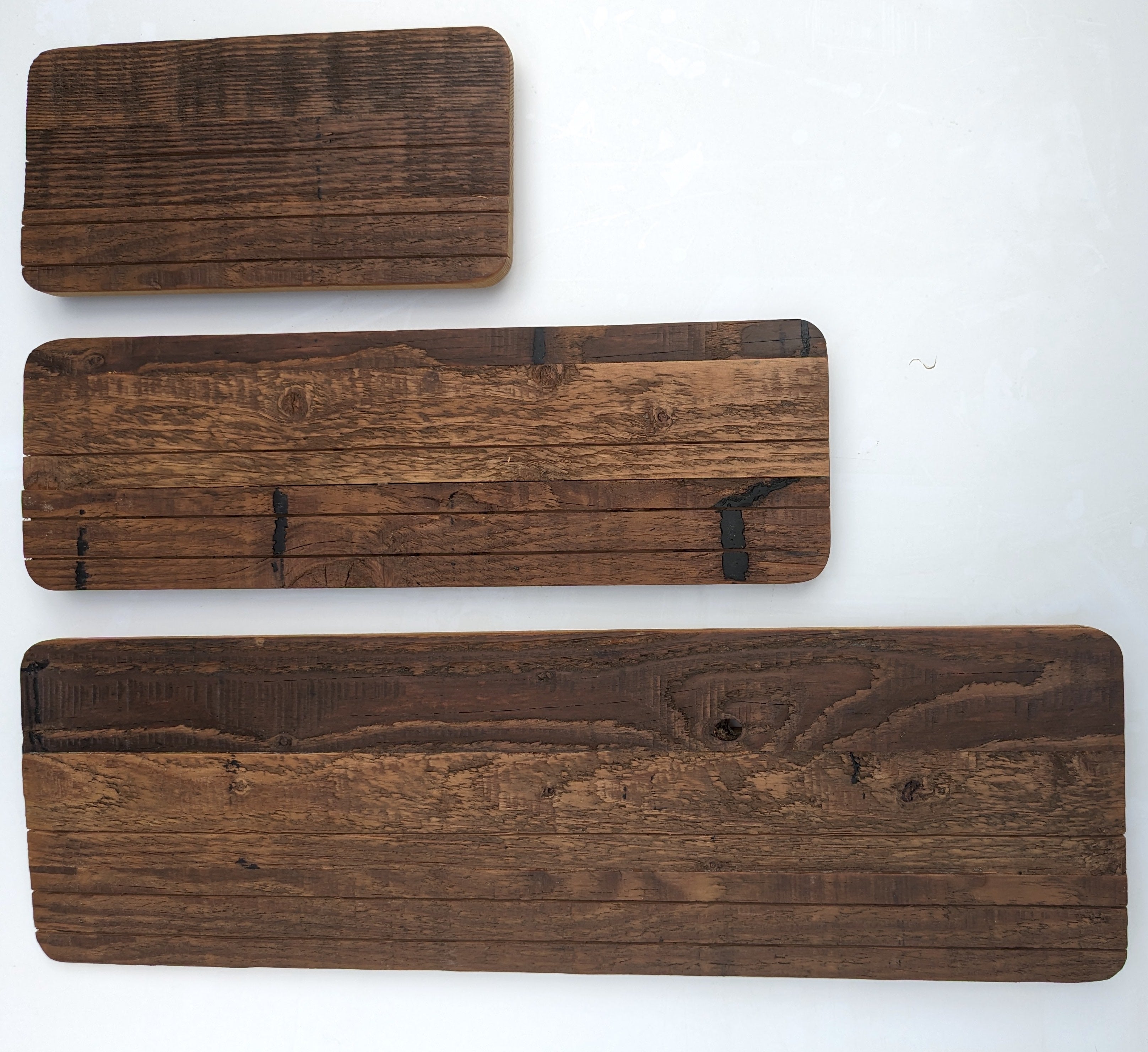 Three Groove Shelves reclaimed wood backer panels in small, medium, and large sizes, showing natural grain and aged dark brown texture, on a white background