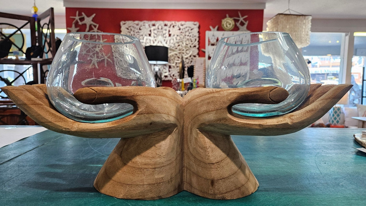 carved wooden hands with two glass terrariums on a table