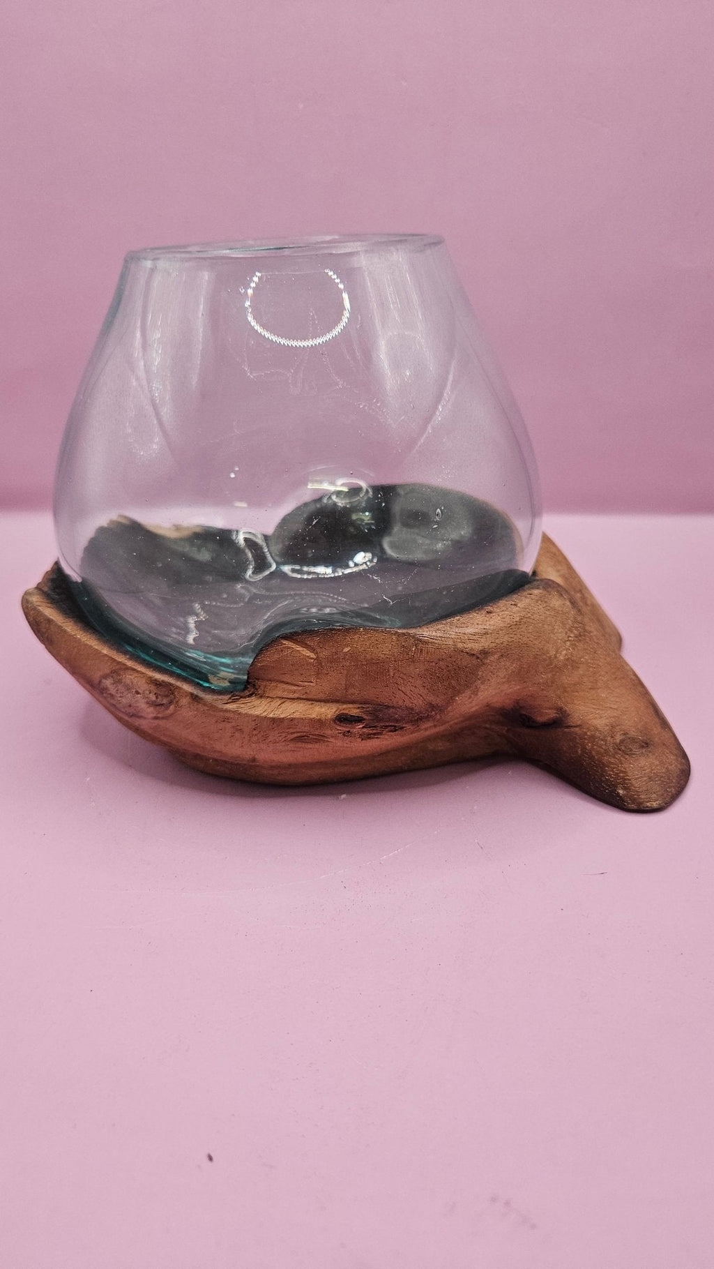 Glass container with wooden base on a pink background