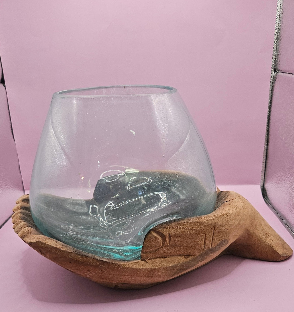 Glass container with a wooden base on a pink surface